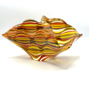 A dynamic glass sculpture with ribbon like curves in shaded of warm amber, yellow and red by Agata Henderson