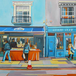 Painting of a street scene with people and shops, featuring 'Lovers Lane' on a building by Mary Leach
