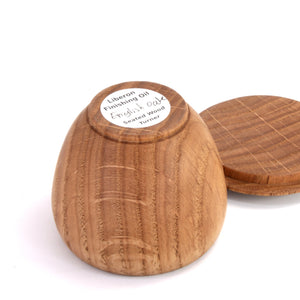 A small turned wood object, likely a coaster or lid, shown on a white background. The bottom has a round sticker reading 'Liberon Finishing Oil English Oak Seated Wood Turner.