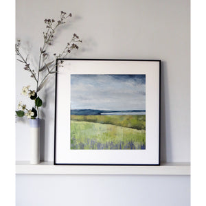 Framed landscape painting on a white wall with decorative branches and flowers.