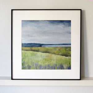 Framed painting of a landscape with green fields and a blue sky.