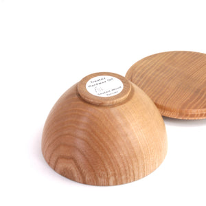A light natural wood bowl with its matching round wooden lid resting behind it on a clean white background. 