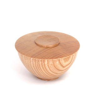 A small round wooden bowl with a matching lid, featuring a natural light brown wood grain pattern, photographed on a clean white background.