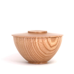 A small wooden bowl with a matching lid, featuring a prominent natural wood grain pattern, set against a plain white background.