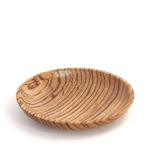 A small oval wooden dish with a prominent natural wood grain pattern, photographed on a clean white background.