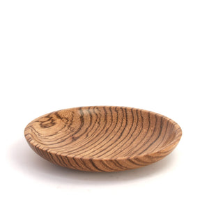 A small oval wooden dish with a prominent wavy wood grain pattern, photographed on a clean white background.