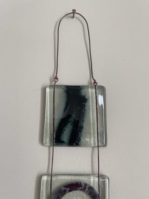 hand made small kiln formed fused glass icon hanging with abstract shapes and patterns made from  metal inclusions in four squares joined together by wire trapped inside the glass by london based glass artist eryka isaak