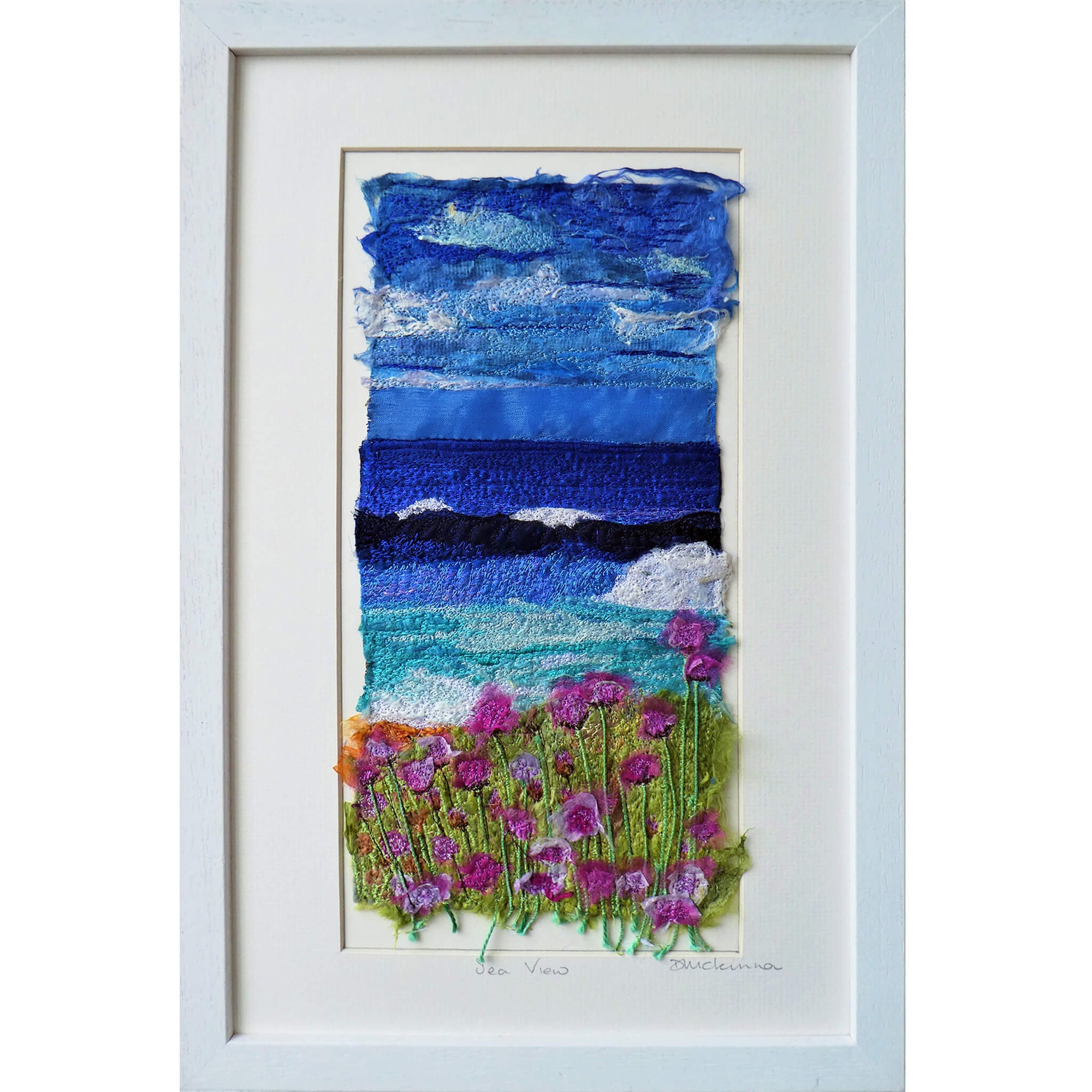 Sea View by Diana Mckinnon silk embroidery artist comprising blue sky, ocean and pink coastal flowers in white frame