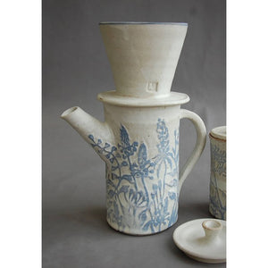 A stoneware coffee pot and filter decorated with light blue wild flowers on white by London ceramicist Jonquil Cook